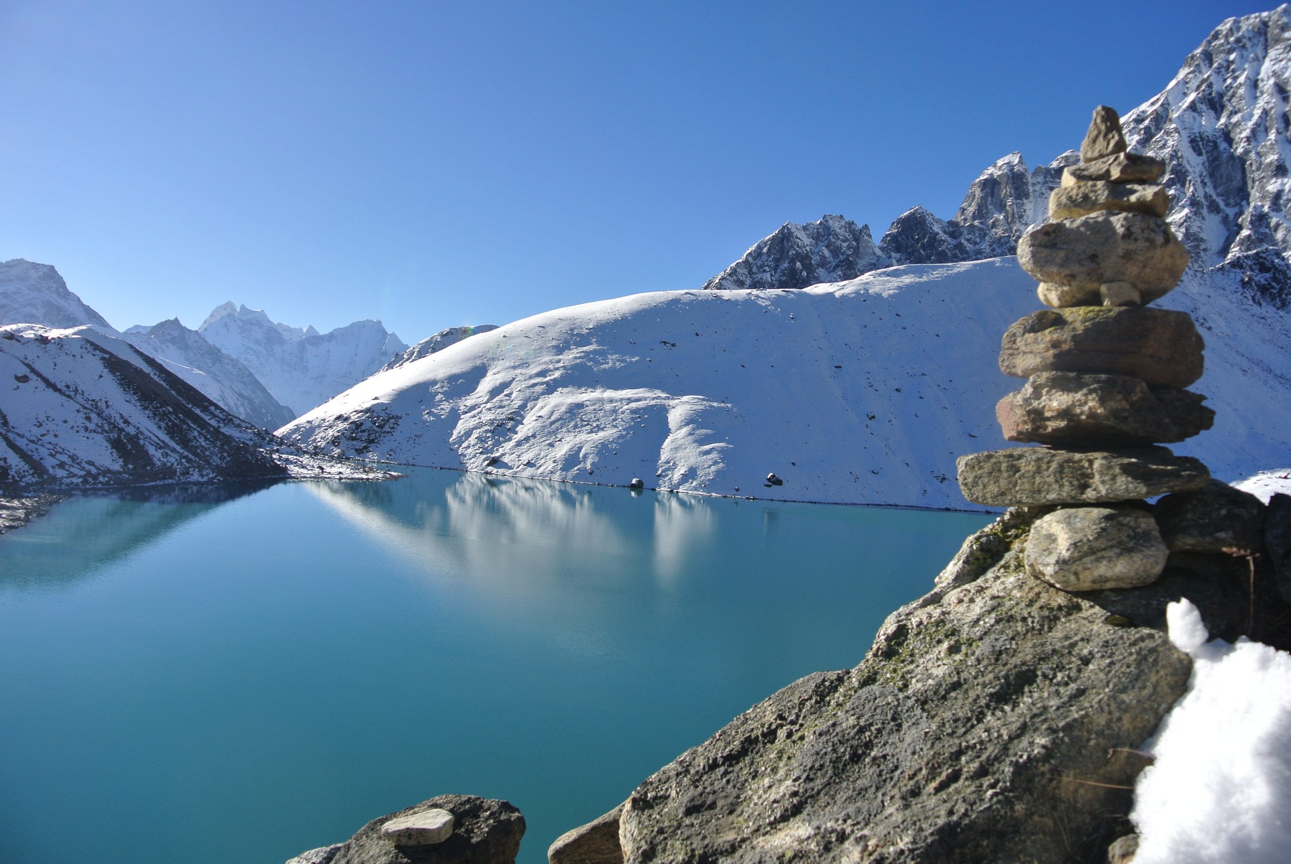 Bergsee im Himalaya mit Steinstapel und weitem Horizont – Symbol für innere Ruhe im Schweigeretreat und Meditationsretreat bei Berlin.