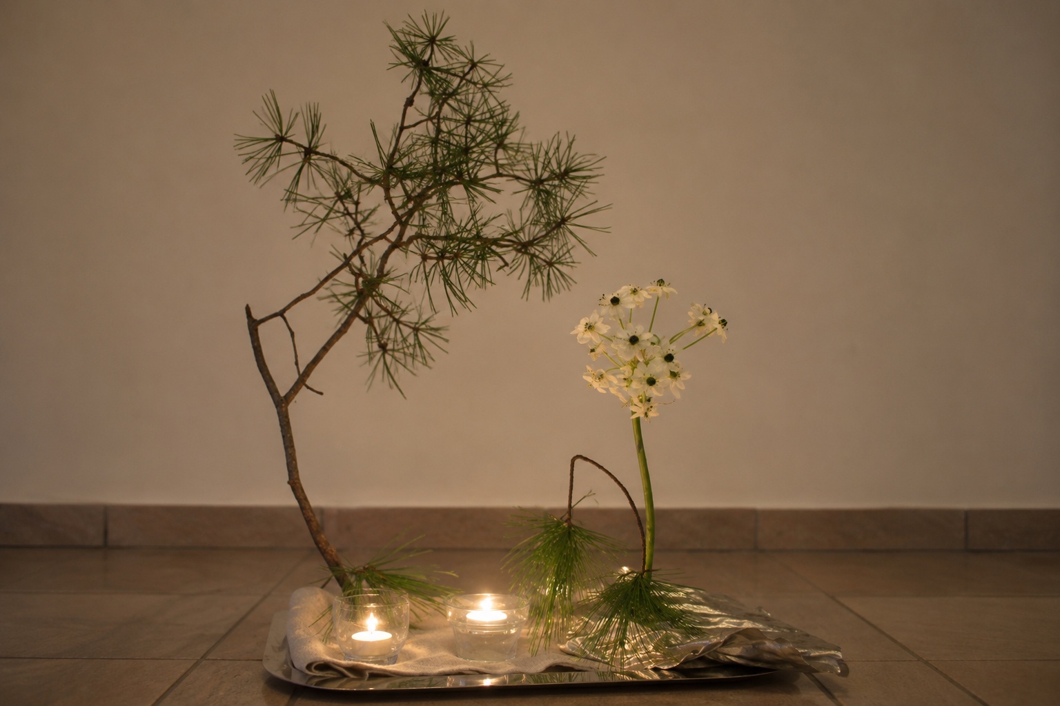 Schweigeretreat im Winter – Dankbares Herz und klarer Geist Meditative Winterdekoration mit Kiefernzweig, weißen Blüten und Kerzen bei einem Schweigeretreat im Winter.